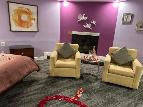 a bedroom with two chairs and a bed and a fireplace at Inn of the Dove - Romantic Luxury Suites with Jacuzzi & Seasonal Fireplace at Harrisburg-Hershey-Philadelphia, PA in Harrisburg