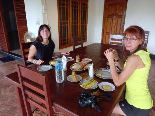 dos mujeres sentadas en una mesa comiendo comida en LLT Tourist Inn and Safari Jeep en Wilpattu