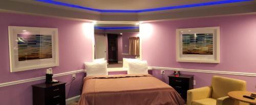 a room with a bed and a chair and purple walls at Inn of the Dove - Romantic Luxury Suites with Jacuzzi & Seasonal Fireplace at Harrisburg-Hershey-Philadelphia, PA in Harrisburg