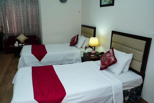 a hotel room with two beds with red and white sheets at Garden Residents Uttara - Lake View in Dhaka