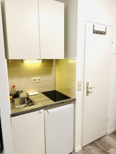 a kitchen with white cabinets and a sink at Sophisticated City Loft in Mainz