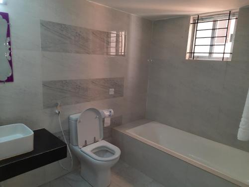 a bathroom with a toilet and a tub and a sink at Garden Residents Uttara - Lake View in Dhaka