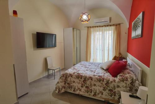 um quarto com uma cama e uma televisão de ecrã plano em Casa San Brasi di Mariano e Lucia em Acireale