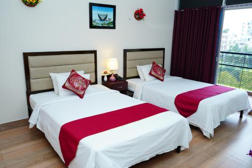 a hotel room with two beds with red and white sheets at Garden Residents Uttara - Lake View in Dhaka