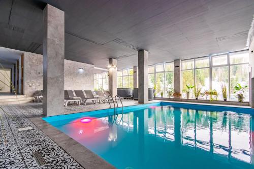 een binnenzwembad met blauw water in een gebouw bij Konopka Forest Home & SPA in Boekovel