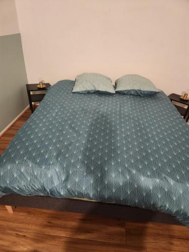 1 cama con edredón azul y 2 almohadas en Plein centre, en Malzéville