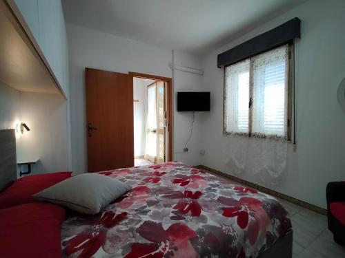 a bedroom with a bed with a red floral bedspread at domu de babbai in Assemini