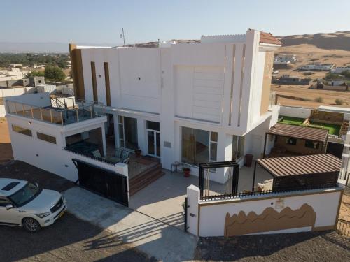 a white house with a car parked in front of it at R61 Sunset Chalet in Muntarib