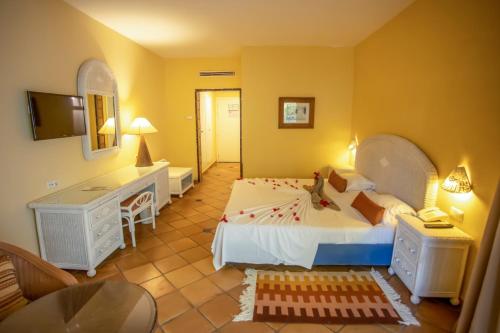 een slaapkamer met een bed, een bureau en een televisie bij Odyssee Resort Thalasso & SPA in Zarzis