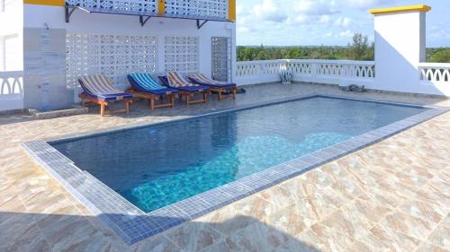a swimming pool on a patio with chairs around it at Casa Marabella A2 in Diani Beach
