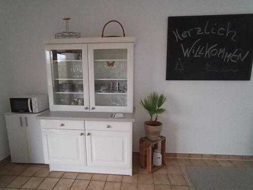 um armário branco num quarto com um vaso de plantas em Ferienwohnung Marell em Großwallstadt