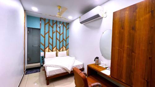 a small bedroom with a bed and a mirror at Hotel Vandana Palace in Surendranagar