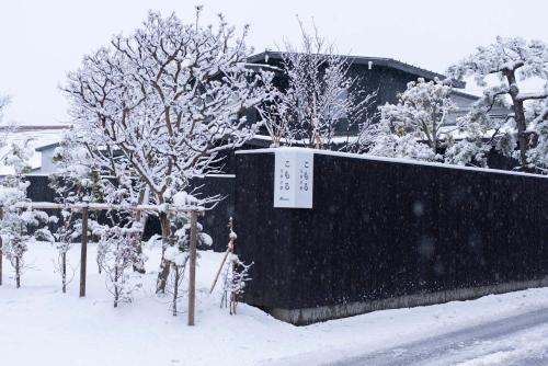 Goshogawara的住宿－こもる五所川原，一座有树木和建筑物的雪覆盖的院子