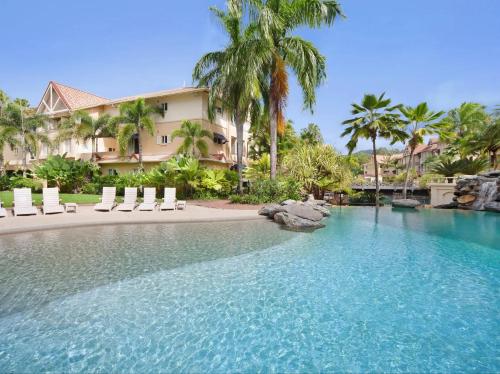 a resort swimming pool with chairs and palm trees at Luxury tropical 2bedroom apartment in resort 4 swimming pools in Cairns North
