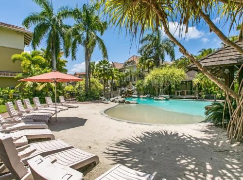 a resort with a pool and chairs and palm trees at Luxury 2 Bedroom apartment, Treetop views, Resort with 4 swimming pools in Cairns North