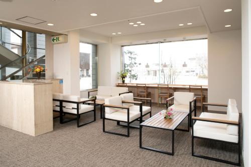 una sala de espera con mesas y sillas en un edificio en Yokote Plaza Hotel, en Yokote