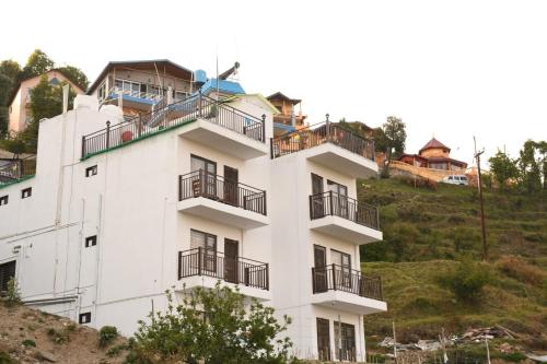 a white building on the side of a hill at Rameshwarm Resort in Mukteswar
