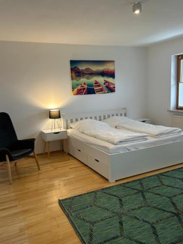 een witte slaapkamer met een bed en een stoel bij Gehobene Ferienwohnung Madera Campesina in Hunderdorf