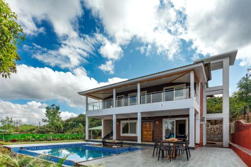 a villa with a swimming pool and a house at Malibu Villa by Hill Staytion in Panchgani