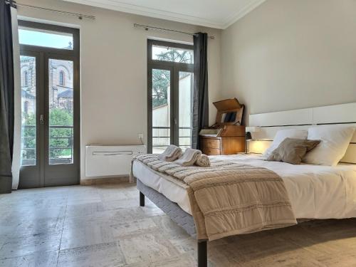a white bedroom with a large bed and a piano at Le Coté Cour - Fibre - Clim - Centre-ville in Albi