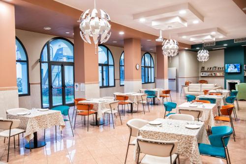uma sala de jantar com mesas, cadeiras e lustres em CallMe Crema - Struttura in centro storico em Crema