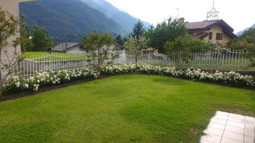 un patio con flores blancas y una valla en Il tiglio en Saint Vincent