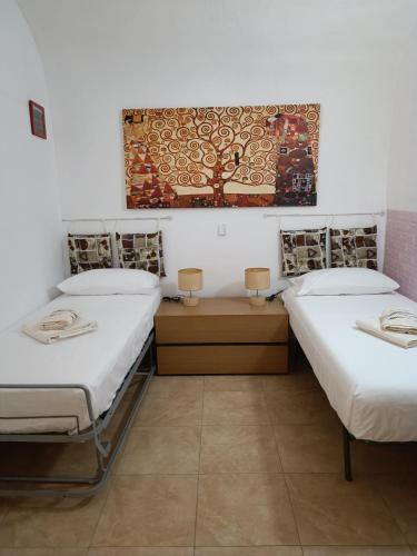 a room with two beds and a painting on the wall at NONNA ADRIANA in Terrasini