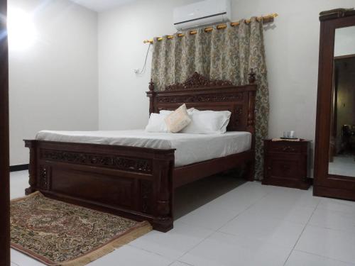 1 dormitorio con cama de madera con sábanas y almohadas blancas en Nursery Inn, en Karachi