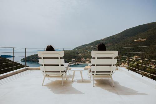 two people sitting in chairs on a balcony looking at the view at 2S Villas Resort in Sivota