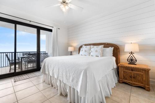 Habitación blanca con cama y balcón. en Grand Pointe 401 en Orange Beach