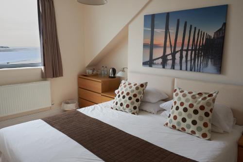 um quarto com uma cama branca com almofadas e uma janela em Fron Haul em Aberdyfi