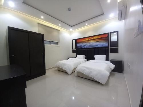 sypialnia z 2 łóżkami i obrazem na ścianie w obiekcie شقق مفروشة - توافيق w mieście Burajda