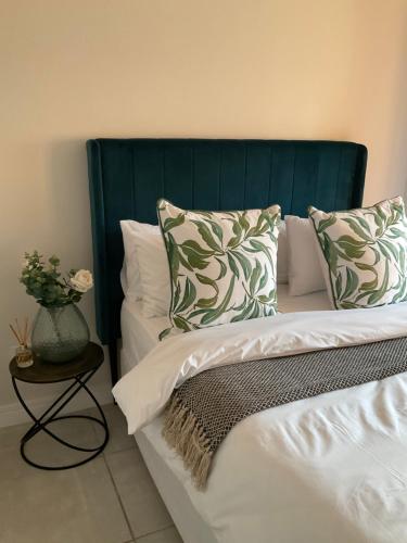 a bed with a green headboard and pillows at Contemporary unit at the Blyde in Pretoria