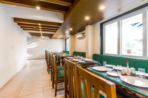 a long dining room with long tables and green chairs at Lar De Oliveira in Porvorim