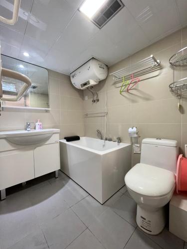 a bathroom with a tub and a toilet and a sink at Chaoyang Joy City Hardcover Apartment in Beijing