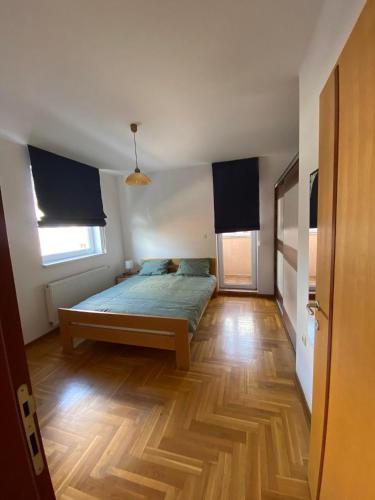 a bedroom with a bed and a wooden floor at D Apartment Free private Parking in Novi Sad