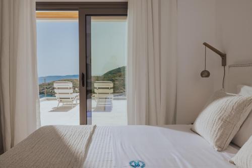 a bedroom with a bed and a balcony with chairs at 2S Villas Resort in Sivota