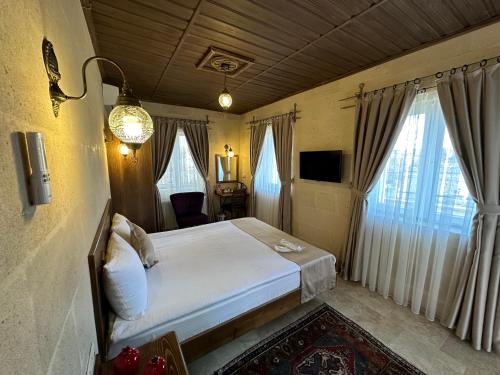 a bedroom with a bed in a room with windows at Virtus Cappadocia Hotel Göreme in Goreme