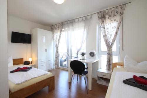 1 dormitorio con 2 camas, escritorio y ventana en Apartments/Wohnungen direkt in Aschaffenburg, en Aschaffenburg