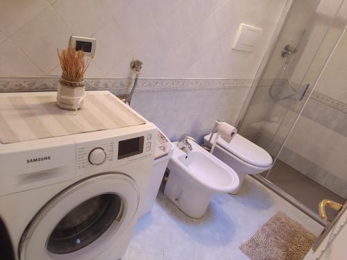uma casa de banho com uma máquina de lavar roupa e um WC em Villetta di montagna em Foza