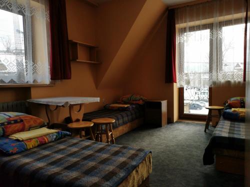a room with two beds and a table and windows at Domek u Stocha in Poronin