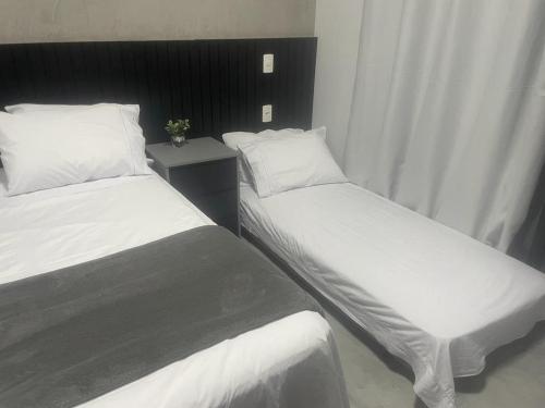 2 Betten in einem Hotelzimmer mit weißer Bettwäsche und Kissen in der Unterkunft Studio Acolhedor e Moderno no Centro de São Paulo! in São Paulo