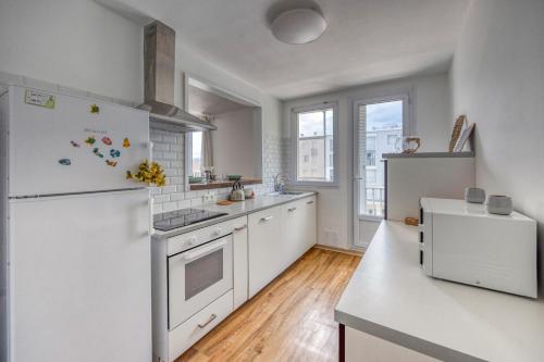 Il comprend une cuisine équipée d'appareils électroménagers blancs et d'un réfrigérateur blanc. dans l'établissement Le Verderet - Jean Perrot - MC2, à Grenoble