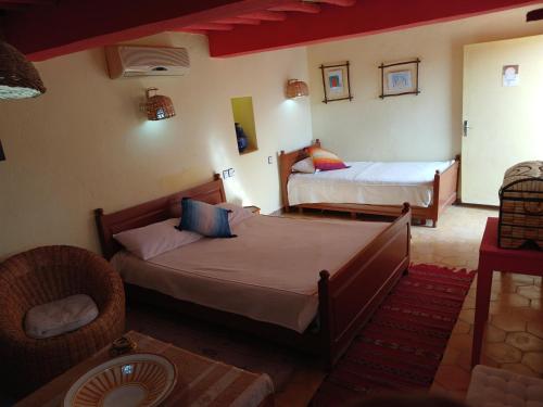 1 dormitorio con 2 camas y 1 silla en chambre d'hôte yamina, en Tafraoute