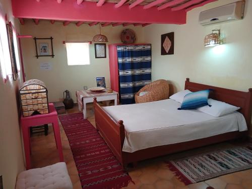 1 dormitorio con 1 cama, 1 mesa y 1 silla en chambre d'hôte yamina en Tafraoute