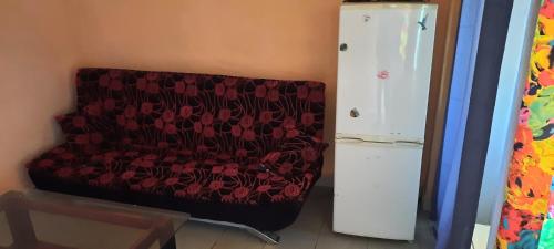 un sofá rojo sentado en una habitación junto a una nevera en Dalle Sutio meublé ETOUG-EBE, en Yaoundé