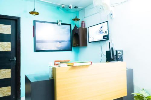 Habitación con escritorio y TV en una pared azul. en Family Friendly Hotel - Near Saket Metro, en Nueva Delhi