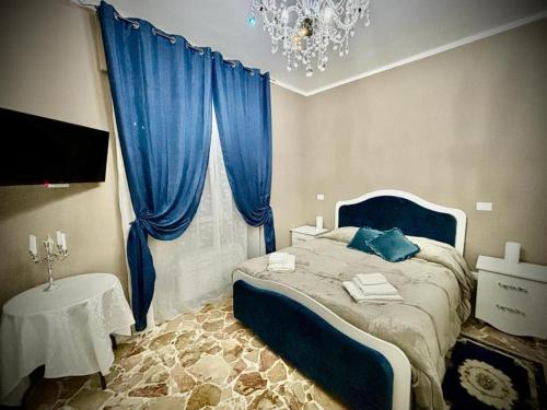 a bedroom with a bed with blue curtains and a chandelier at Il Castello Di Venere in Rota d'Imagna