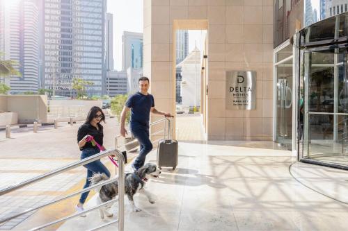 a man and a woman walking a dog down the stairs at Delta Hotels by Marriott City Center Doha in Doha