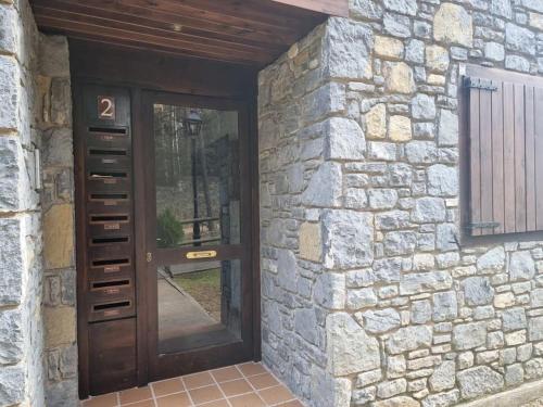 a stone house with a wooden door and a stone wall at Piso Acogedor en La Molina in La Molina